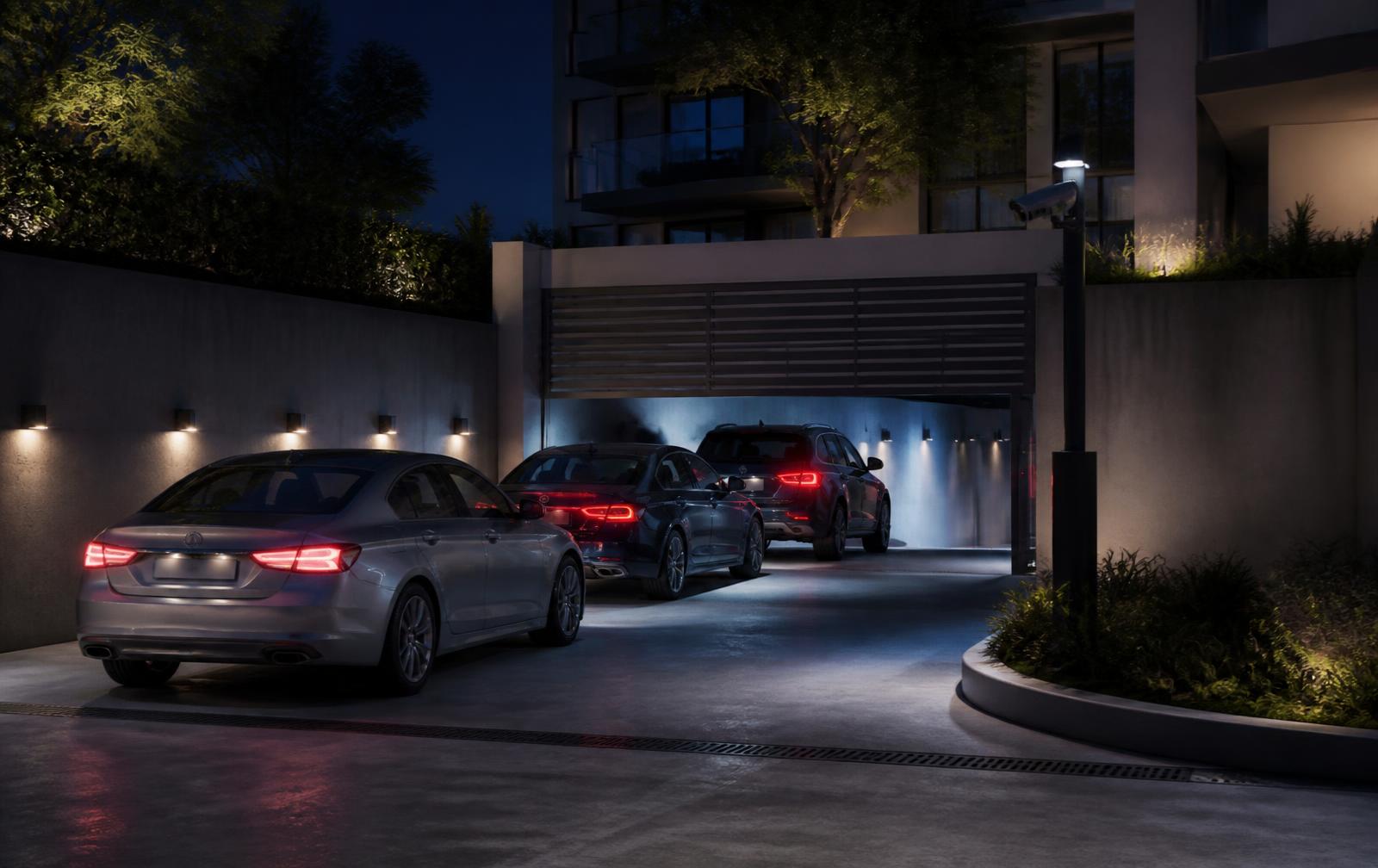 Entrada de garaje de un edificio residencial de noche con varios vehículos y cámara LPR